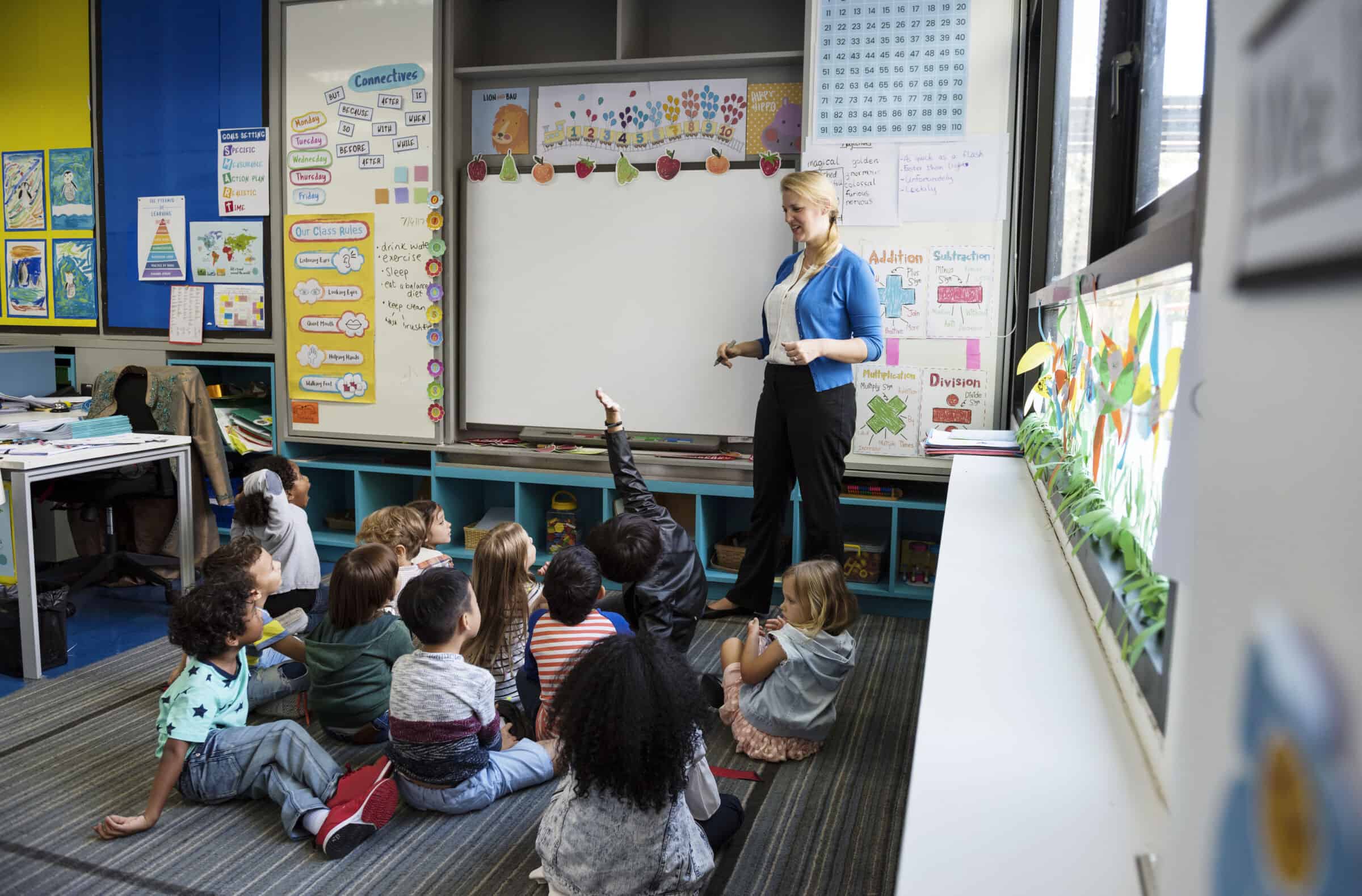 Kindergarten students sitting on the floor listening to teacher